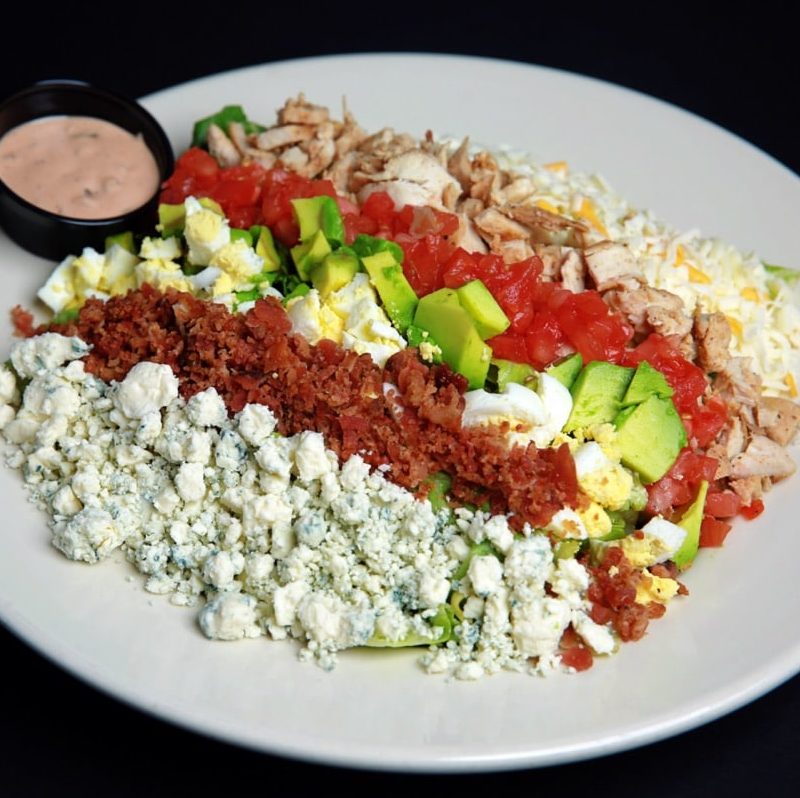 Salad greens topped with grilled chicken, diced egg, diced avocado, diced tomato, bleu cheese crumbles and diced bacon. Served with your choice of dressings.
