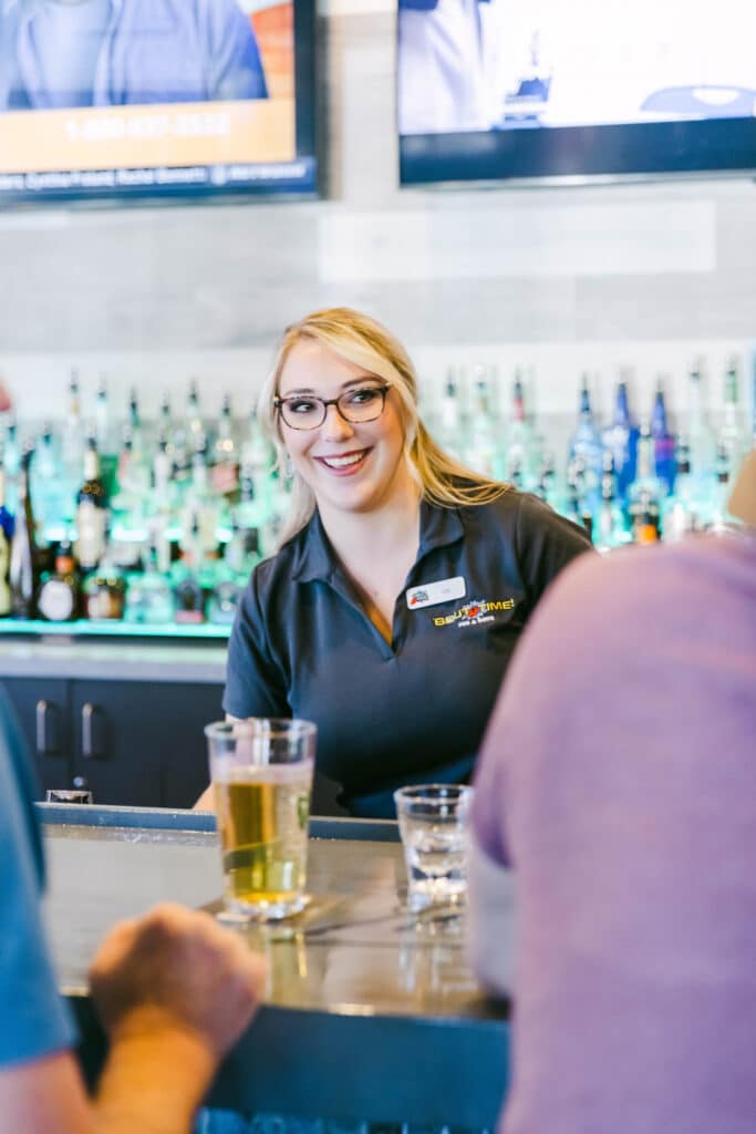 Female employee smiling at customers at the bar